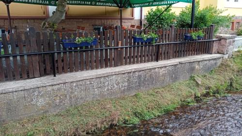 a fence with potted plants on it next to a river at Landgasthof Zum Heidekrug in Bad Orb