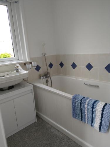 een witte badkamer met een bad en een wastafel bij Mulberry Lawn Apartments in Brading