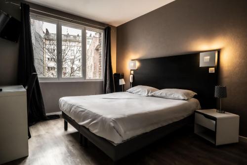 a bedroom with a large bed and a large window at Hotel De Quebec in Rouen