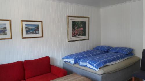 a bedroom with a bed and a red couch at Apartment Bystranda - City Beach in Kristiansand