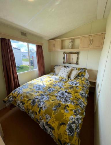 a bedroom with a bed with a yellow floral comforter at Steeple Bay F79 in Steeple
