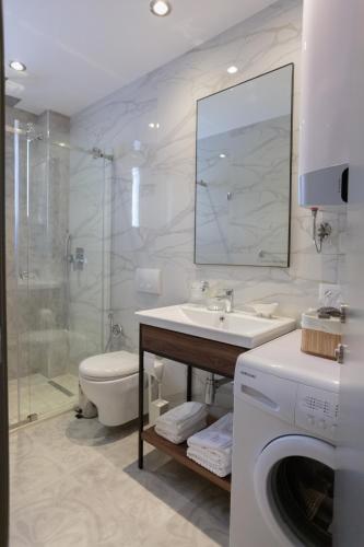 a bathroom with a sink and a toilet and a washing machine at Porta Apartament in Vlorë