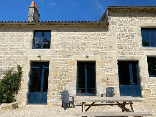 a picnic table in front of a stone building at Château des Loups - Les Cèdres Bleus in Échiré