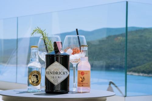 a table with two bottles and two glasses of wine at SUNSET APARTMENTS RABAC in Rabac