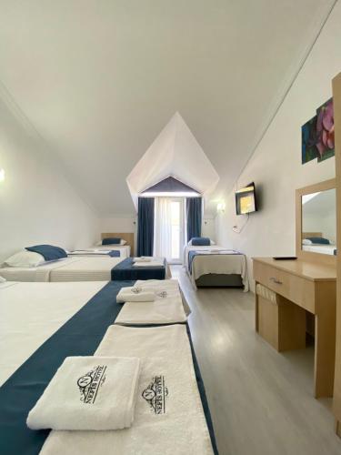 Habitación con 3 camas, lavabo y espejo. en Nefis Hotel Ölüdeniz, en Ölüdeniz