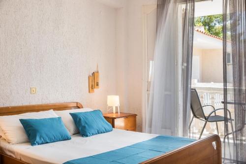 a bedroom with a bed with blue pillows and a balcony at Sunset Beach Appartments in Minia