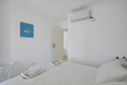 une chambre blanche avec un lit avec deux serviettes dessus dans l'établissement Barrosa Frente al Mar, à Chiclana de la Frontera