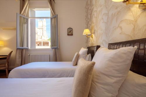 a hotel room with two beds and a window at Hôtel La Résidence in Narbonne