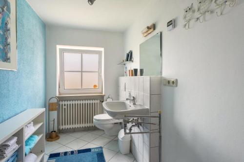 ein Bad mit einem Waschbecken, einem WC und einem Fenster in der Unterkunft Ferienhaus Carin in Utting