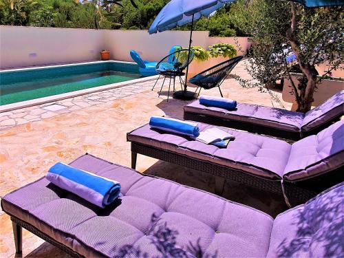 a purple couch sitting next to a swimming pool at Villa Spark with heated pool in Rogoznica Zecevo in Zečevo Rogozničko