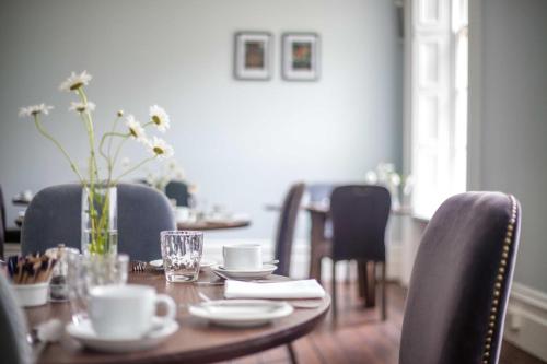 una mesa de madera con sillas y una mesa con un jarrón de flores en Caistor Hall, en Norwich