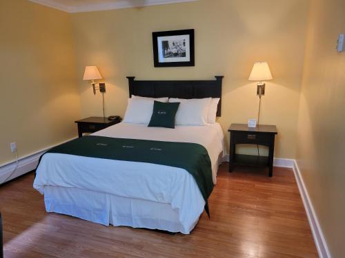 a bedroom with a large bed and two night stands at Grenfell Heritage Hotel & Suites in St. Anthony