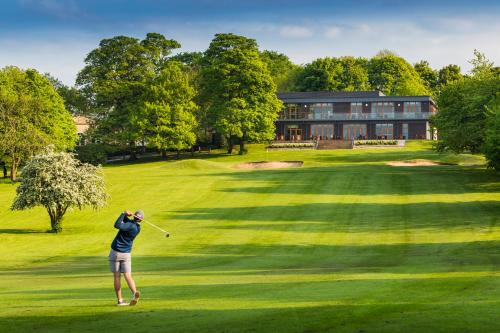 a person swinging a golf club on a green at Oulton Hall Hotel, Spa & Golf Resort in Leeds