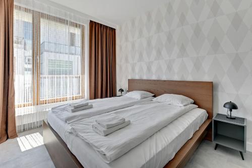 a large bed in a room with a large window at Dom & House - Apartments Nadmorski Park in Gdańsk