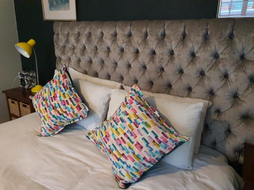 a bed with two pillows and a headboard at Happy colourful cottage in Johannesburg
