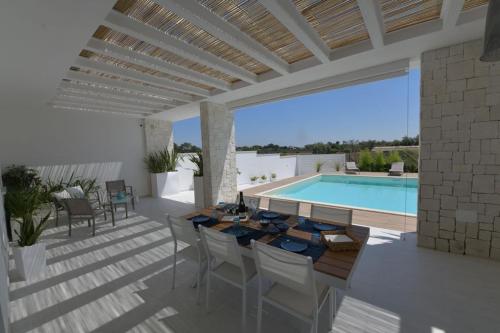 eine Terrasse mit einem Tisch und Stühlen sowie einem Pool in der Unterkunft Il marchese in piscina in San Pietro in Bevagna