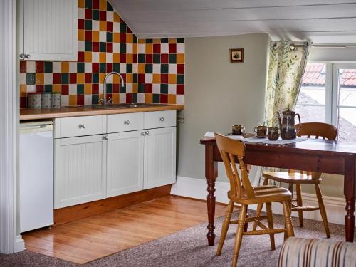 a kitchen with white cabinets and a table with chairs at The Martlet Inn in Wellington