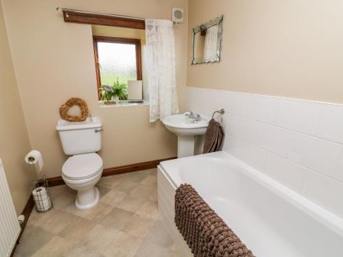 a bathroom with a tub and a toilet and a sink at 1 Netherbeck Barn in Carnforth