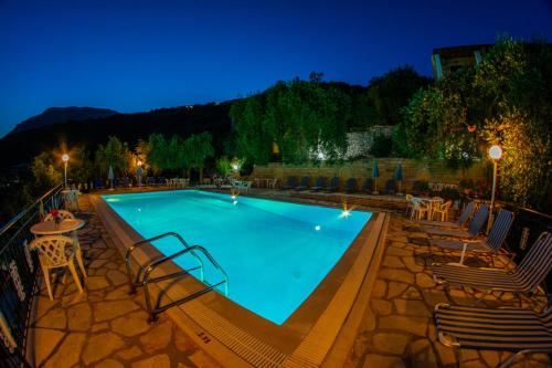 a swimming pool at night with chairs and tables at Amalia Complex in Nisakion