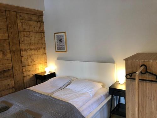 a bedroom with a bed and two tables with lamps at Sisters Beach Apartments in Liepāja