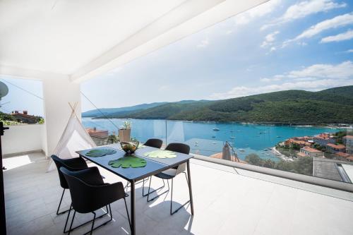 a room with a table and chairs on a balcony at SUNSET APARTMENTS RABAC in Rabac