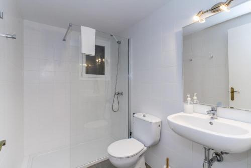 a white bathroom with a toilet and a sink at Apartamentos Ses Anneres in Cala en Blanes