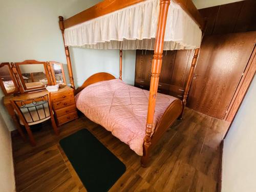 a bedroom with a canopy bed and a wooden floor at Lovely house not far from the beach, near Protaras in Dherinia