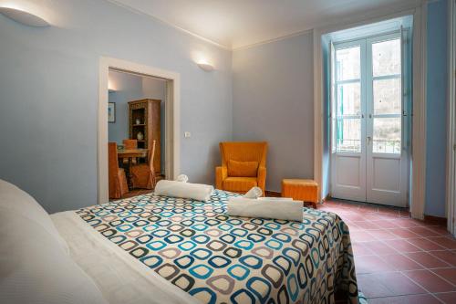 um quarto com uma cama, uma cadeira e uma janela em I Tre Balconi di Via Roma Apartment em Siracusa