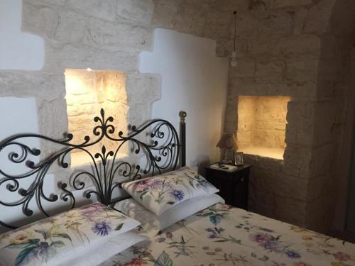 een slaapkamer met een bed met een smeedijzeren hoofdeinde bij Trullo Masso Antico in Alberobello