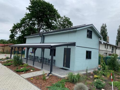 a blue house with a porch and tables in a garden at Turkusowy Zakątek in Międzyzdroje