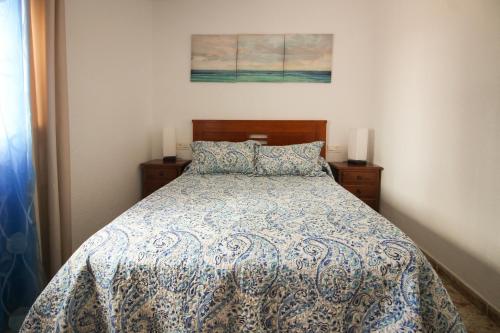 Un dormitorio con una cama con un edredón azul y blanco. en Pueblo Andaluz 921, en Torrox Costa