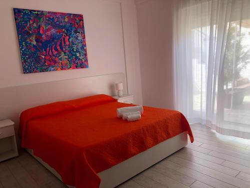 una camera da letto con un letto con una coperta rossa e una finestra di Al Saliceto Hotel a Patti