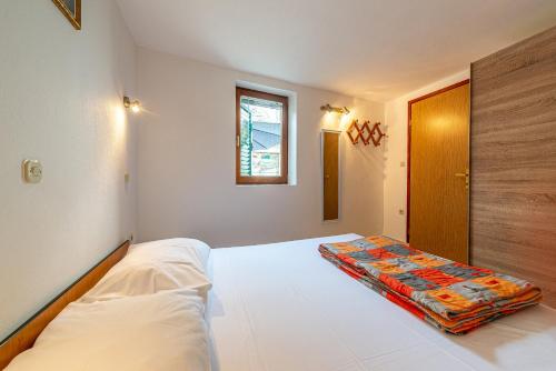 a bedroom with a white bed with a colorful blanket on it at Apartment Bura in Primošten