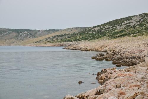 a body of water with rocks and mountains in the background at Apartment Olive in Jovići