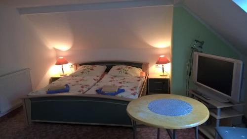a bedroom with a bed and a table and a tv at Pension Zschirnsteinbaude in Kleingießhübel