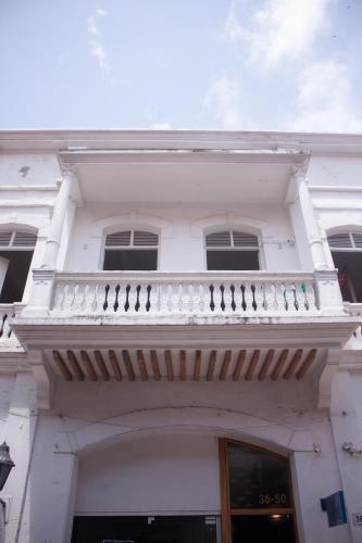 a white building with a balcony on top of it at Hostal Badillo SV in Cartagena de Indias