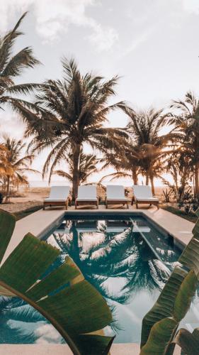 a swimming pool with chairs and palm trees at Casa Kuaa in Brisas de Zicatela