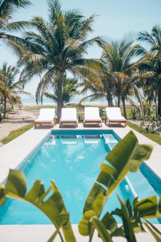 a swimming pool with chairs and palm trees on the beach at Casa Kuaa in Brisas de Zicatela