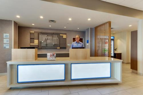 a man standing behind a counter in a lobby at Holiday Inn Express - Wilmington - Porters Neck by IHG in Wilmington