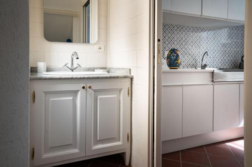 uma casa de banho branca com um lavatório e um espelho em I Tre Balconi di Via Roma Apartment em Siracusa