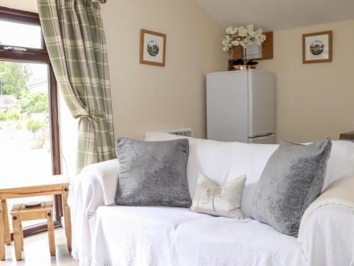 een woonkamer met een witte bank met kussens bij Lannlyvri Lodge in Bodmin