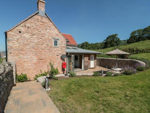 a brick house with a patio and an umbrella at Lilac Cottage in Wells
