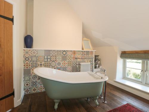 a bath tub in a bathroom with a tile wall at Lilac Cottage in Wells