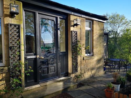 a brick house with a black door and a patio at Kell House Bed & Breakfast in Pateley Bridge