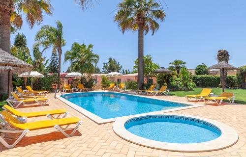 a pool with chairs and a bunch of palm trees at L - Wellness Farm in Lagos