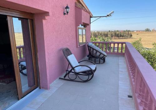 a pink house with two chairs on a balcony at Equi Palace & SPA Near Aeroport in Berrechid