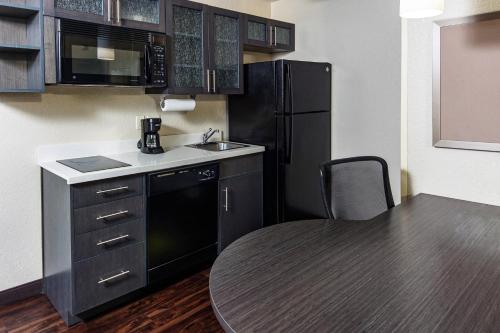 a small kitchen with a table and a black refrigerator at Candlewood Suites Appleton by IHG in Appleton