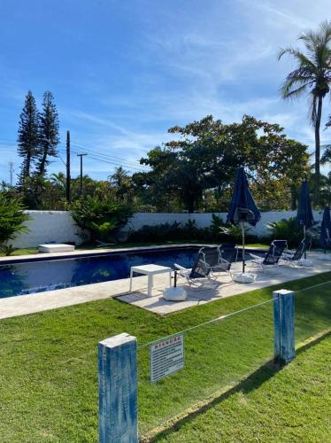 a swimming pool with chairs and umbrellas next to a pool at Pousada Vila Novo Tempo in Guarujá