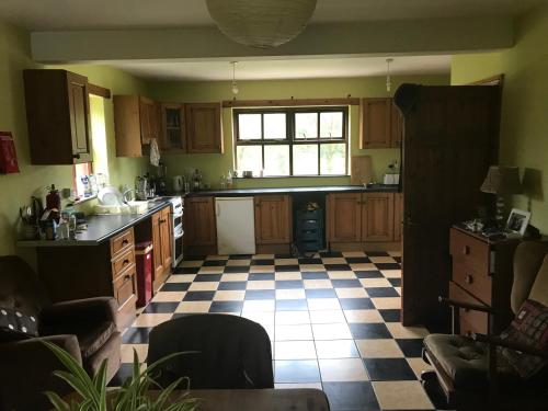 a kitchen with wooden cabinets and a checkered floor at Teach an Ghleanna in Glengarriff