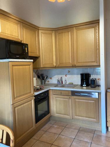 - une petite cuisine avec des placards en bois et un four micro-ondes dans l'établissement Appartement dans chalet typiquement savoyard au pied des pistes, à La Norma